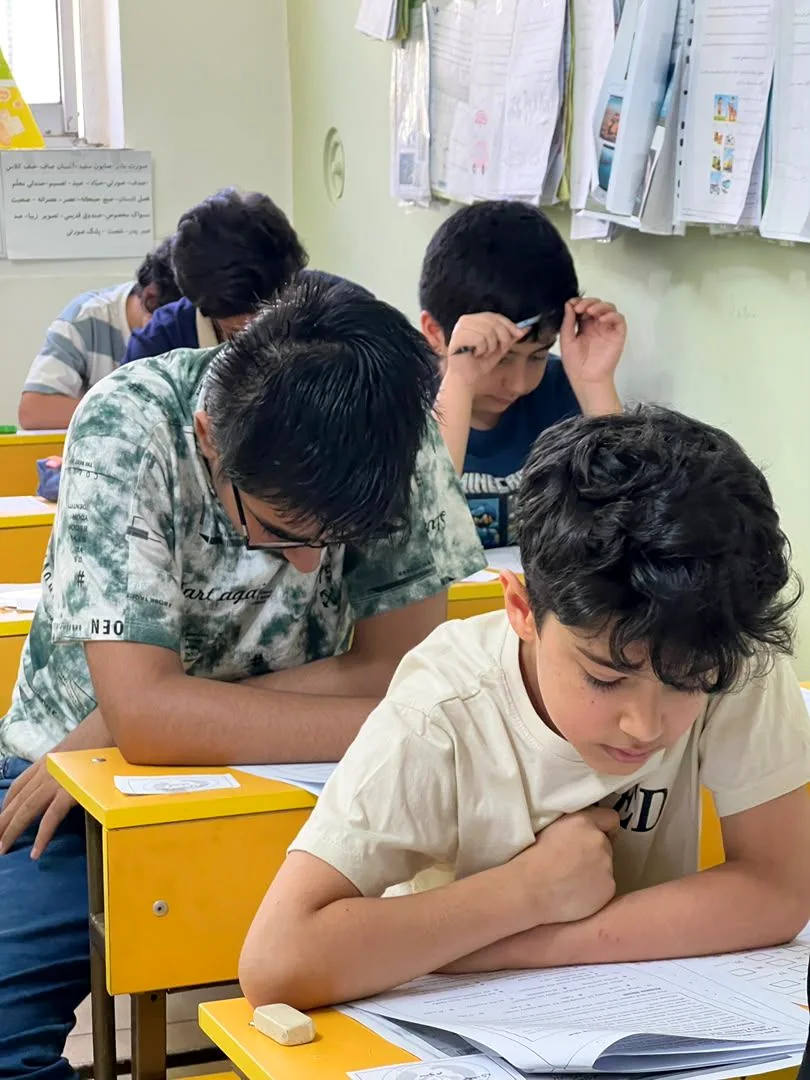 Young scholars concentrating on papers at bright yellow desks